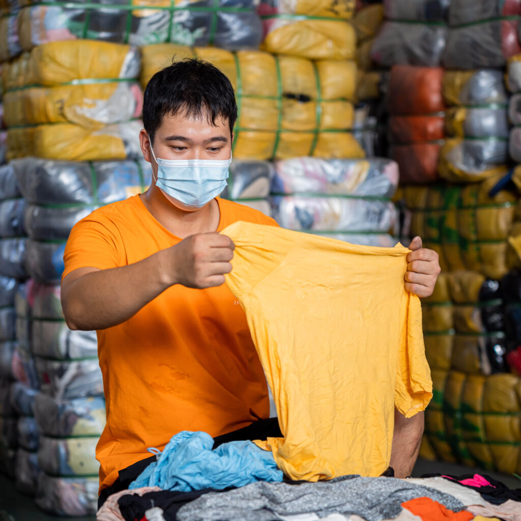 A seasoned inspector scrutinizes the quality and sturdiness of the used clothing.